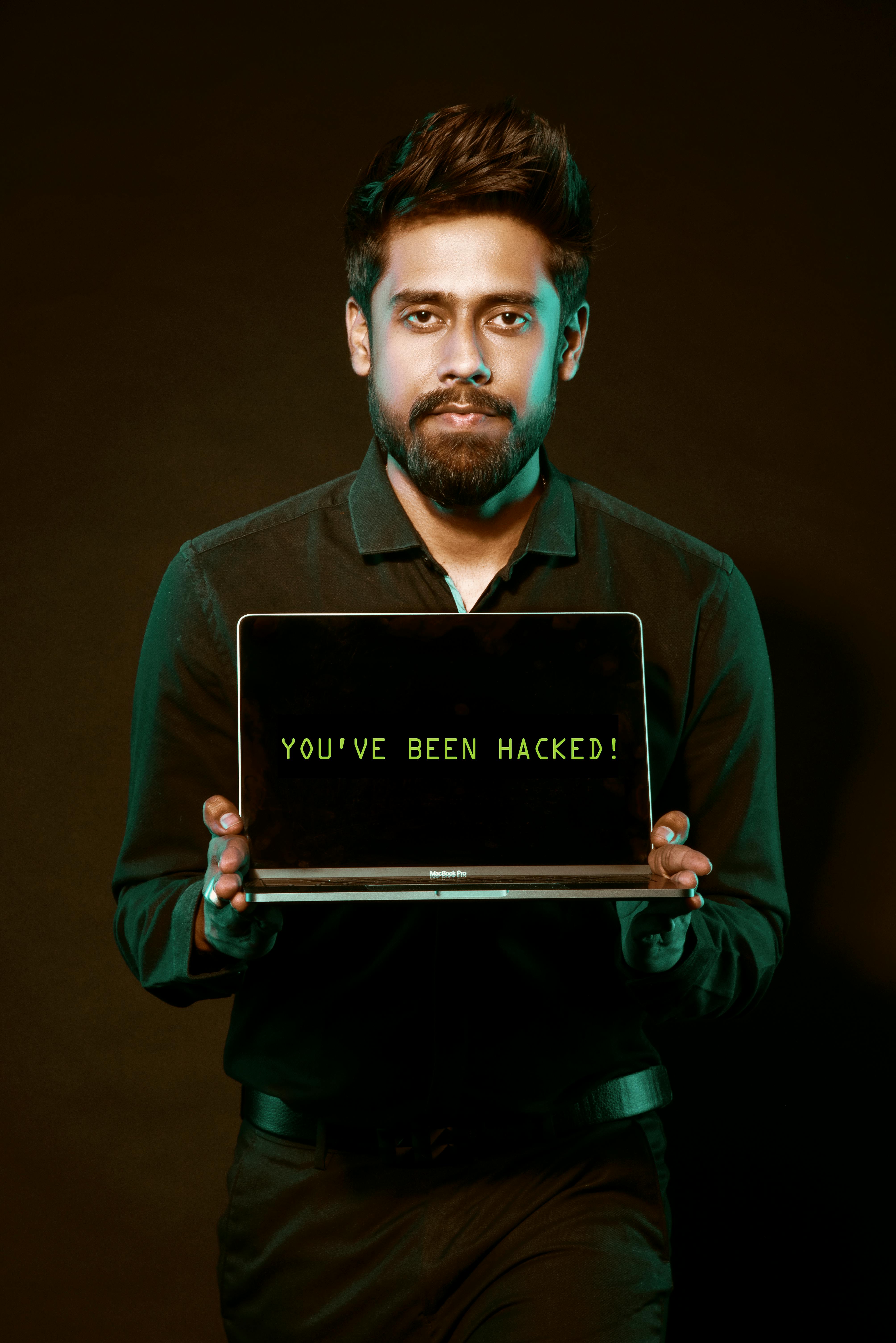 A man showing a laptop with a 'You've been hacked' message, symbolizing cyber security threats.